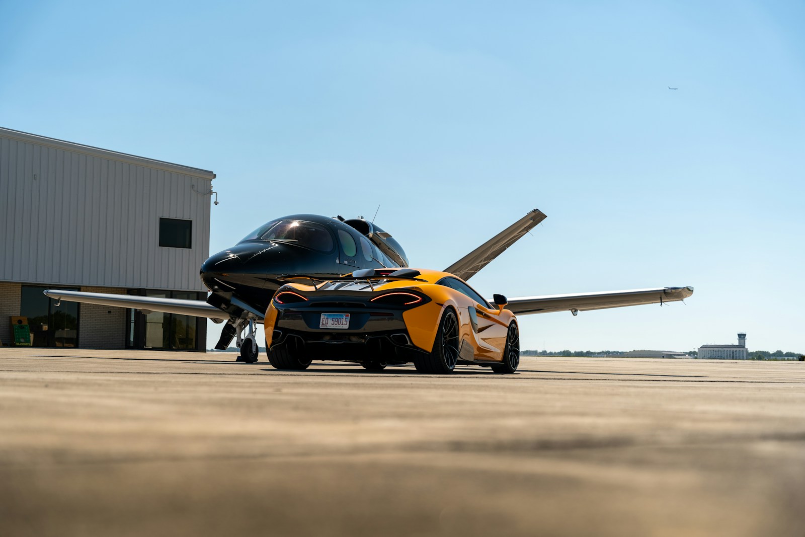 A black and yellow sports car parked in front of a hangar